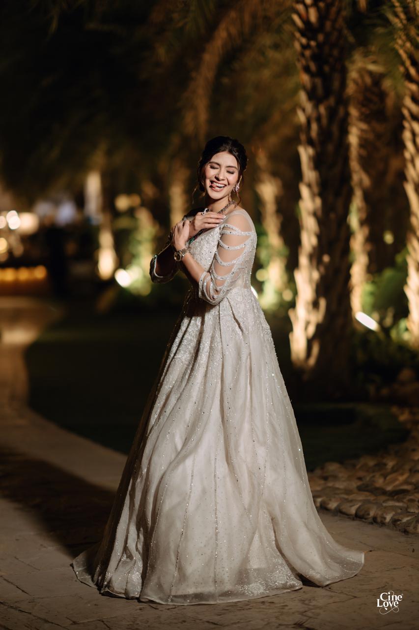 A client smiling in her bespoke ivory gown in an evening garden